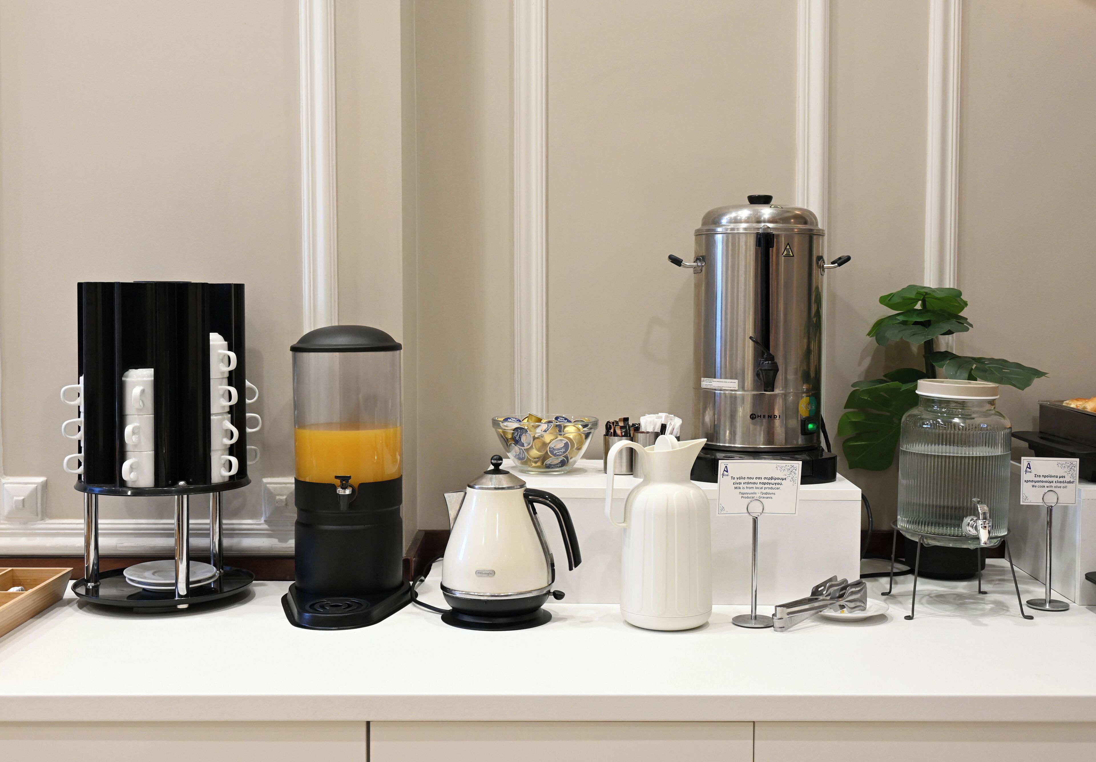 A kitchen counter with various coffee and tea-making equipment, including a coffee press, a milk frother, and a water dispenser.