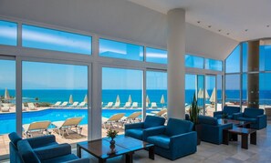 A spacious indoor area with large windows offering a view of a pool and beach chairs.