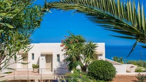 A modern building with a flat roof, surrounded by lush greenery and a clear blue sky. - Scaleta Beach (Rethymno)
