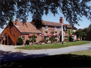 A traditional pub with a brick facade, outdoor seating, and a signboard. - The Longham White Horse (Dereham)