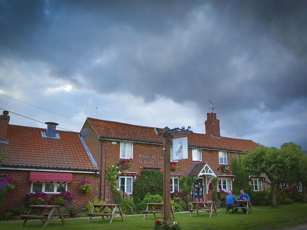 A traditional pub with a red-tiled roof, outdoor seating, and a sign reading "The White Horse at Longnams."