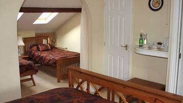A bedroom with two beds, a wooden bench, a skylight, and a white door.