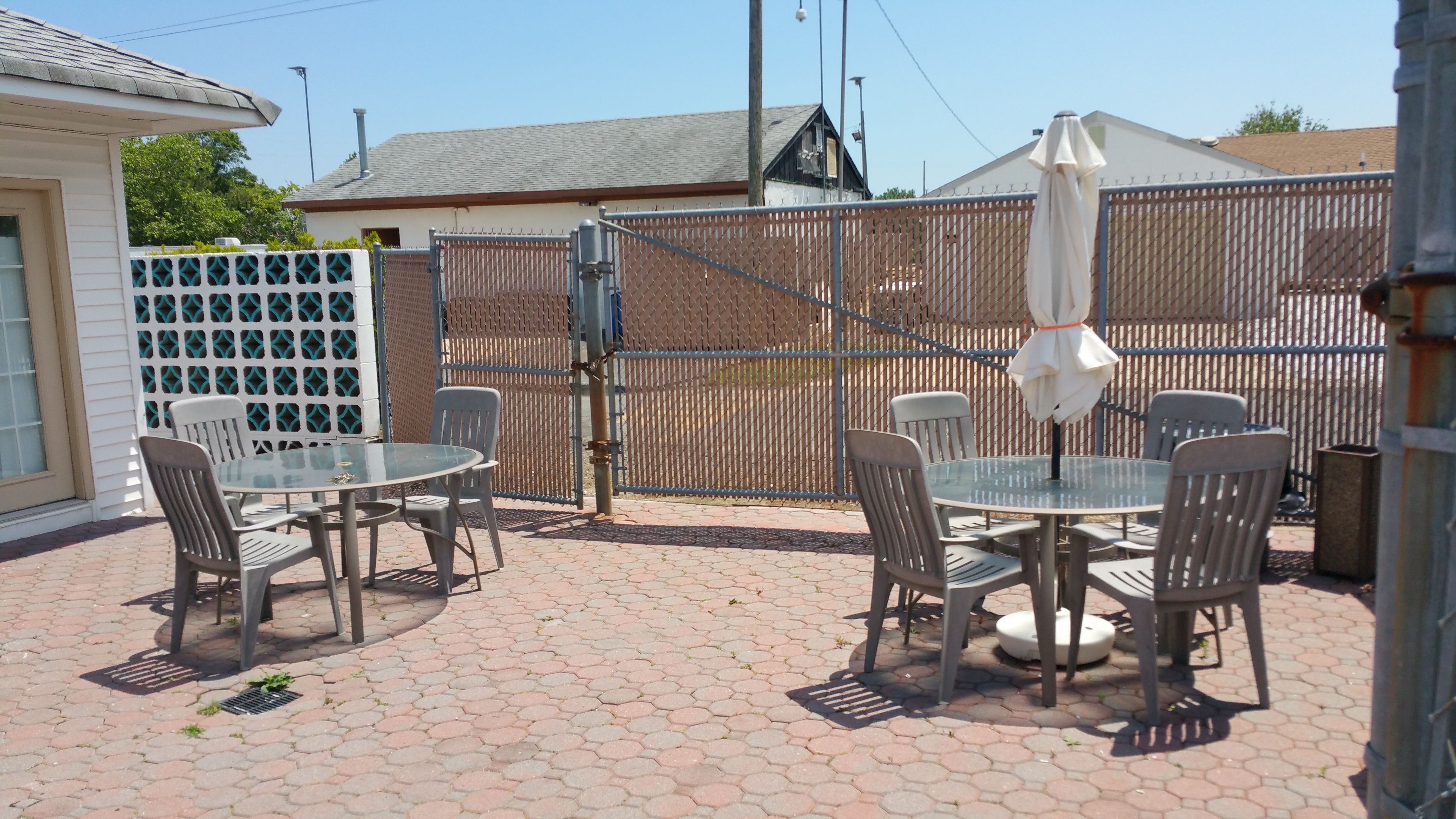 Une terrasse extérieure avec des carreaux hexagonaux, une table en verre et des chaises en métal.