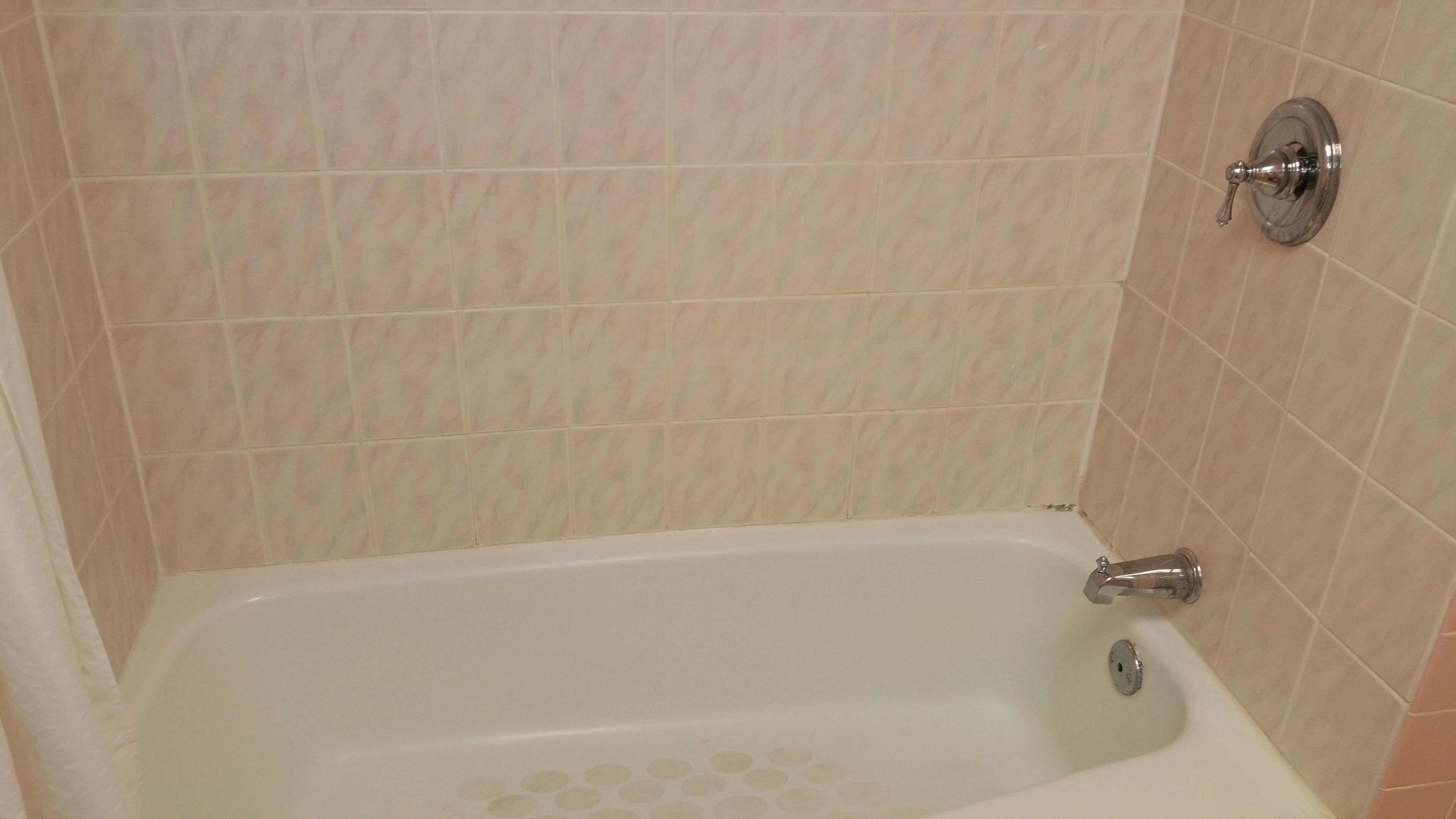 A bathroom with a bathtub, tiled walls, and a showerhead.