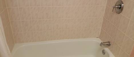 A bathroom with a bathtub, tiled walls, and a showerhead.