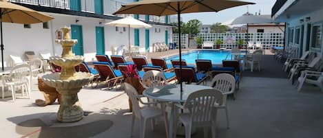 Een buitenzwembad, ligstoelen bij het zwembad