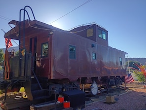 A vintage train caboose with a small cabin, a clock, and an American flag.