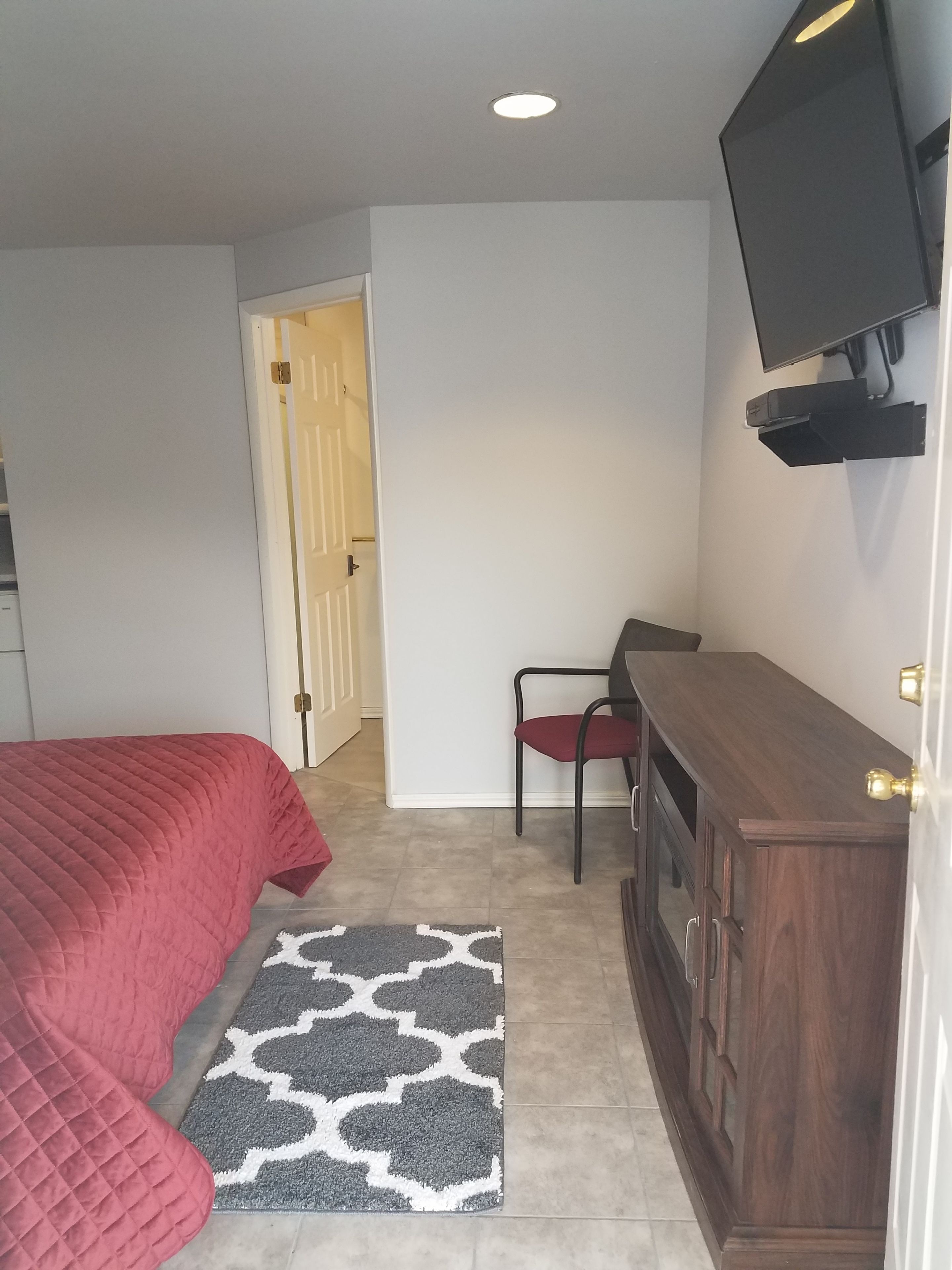 A bedroom with a bed, a desk, a chair, a TV, and a wardrobe.