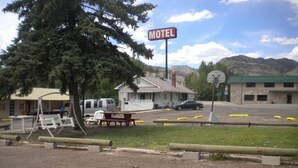 A motel with a sign, picnic tables, and a parking lot. - Riverside Motel (Helper)