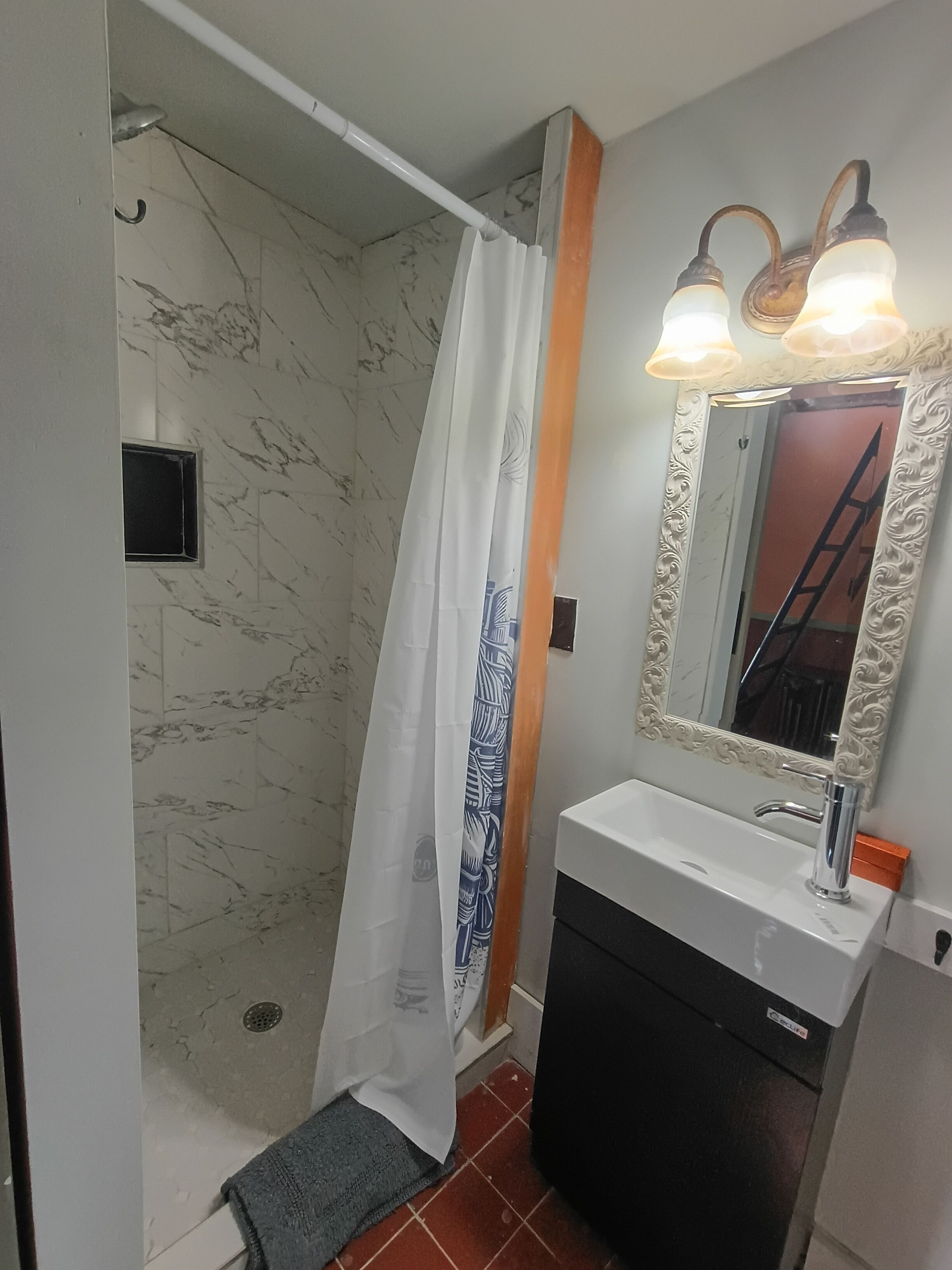 A bathroom with a shower, a sink, and a mirror with lights.