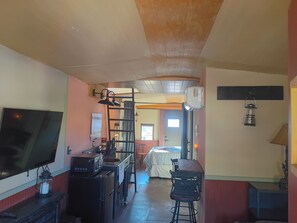 Una cocina con televisión, estufa y barra con taburetes.