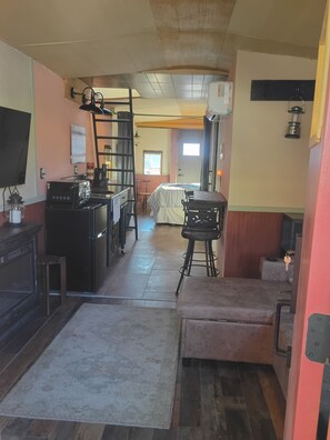 Cocina con refrigerador, estufa y pileta. Hay un comedor con mesa y sillas. Un televisor está montado en la pared.