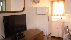 A compact kitchen with a wooden counter, a refrigerator, a microwave, and a sink. - Riverside Motel (Helper)