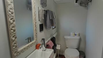 Um banheiro compacto com pia branca, espelho com moldura decorada, vaso sanitário e porta-toalhas.
