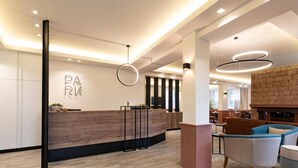 Un área de recepción moderna con un mostrador de madera, una zona de estar con sofás y una chimenea.