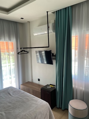 A hotel room with a bed, a TV mounted on the wall, a small table, and a bench. - Park (Alexandroupoli)