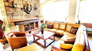 Una sala de estar con chimenea de piedra, sofá de cuero y una mesa de centro.