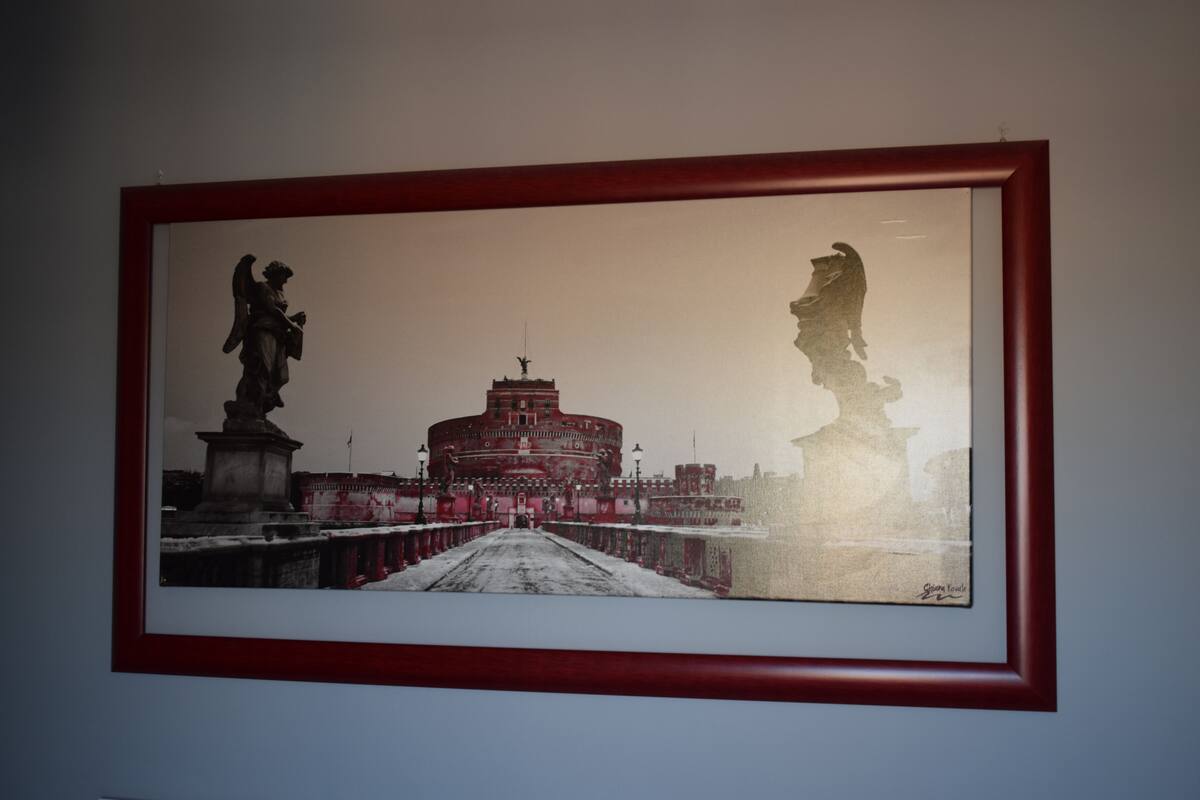En inramad tavla som föreställer en historisk byggnad med statyer och en bro.