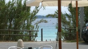 Outdoor seating with tables and chairs, a view of the sea, and a parked car. - Duna Hotel (Sanxenxo)