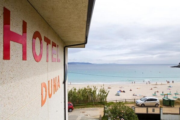 Un hotel llamado "DUNA HOTEL" con vista a una playa y al mar.