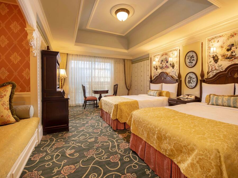 Une chambre d’hôtel avec deux lits, un bureau, une chaise et une grande fenêtre avec des rideaux.
