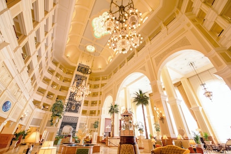 Un lobby espacioso con techos altos, candelabros ornamentales y varios pisos.