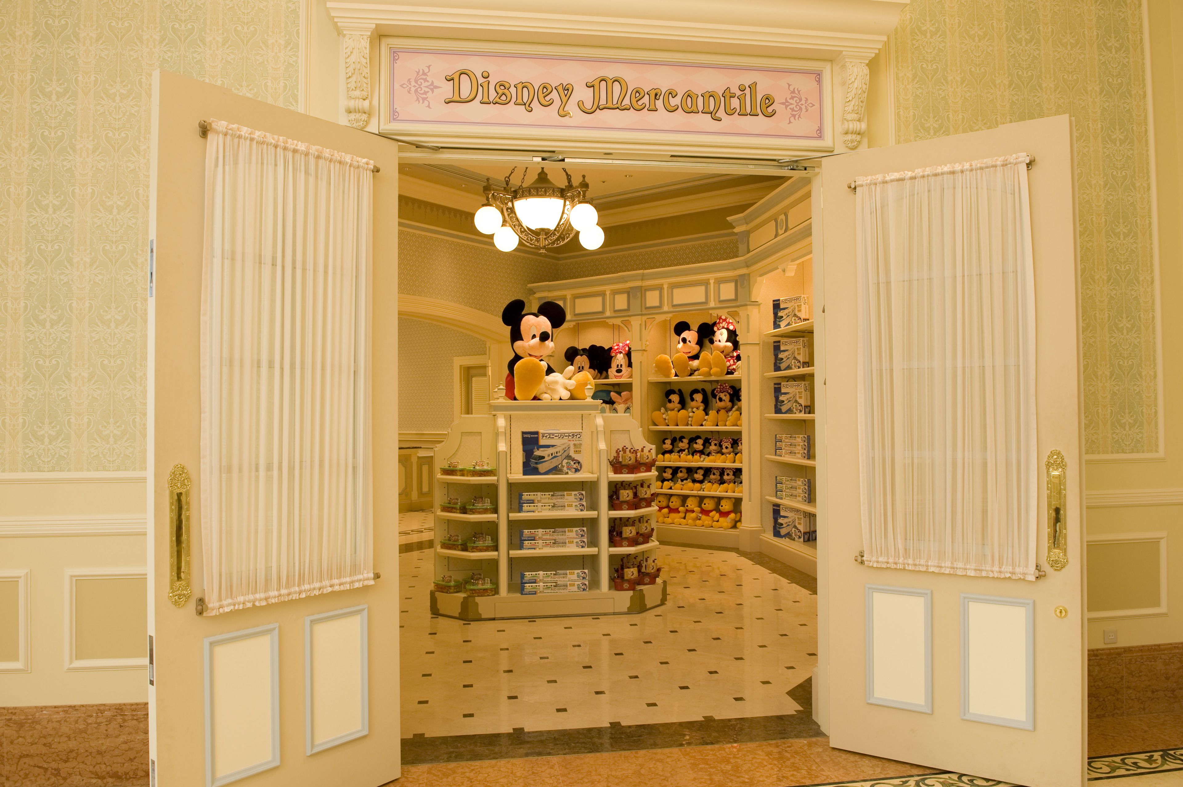 En öppen dörr leder in till ett rum med hyllor fulla av Disney-produkter och en statyett av Musse Pigg.