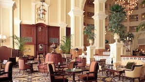 A spacious lobby with multiple seating areas, a grand chandelier, and decorative plants.