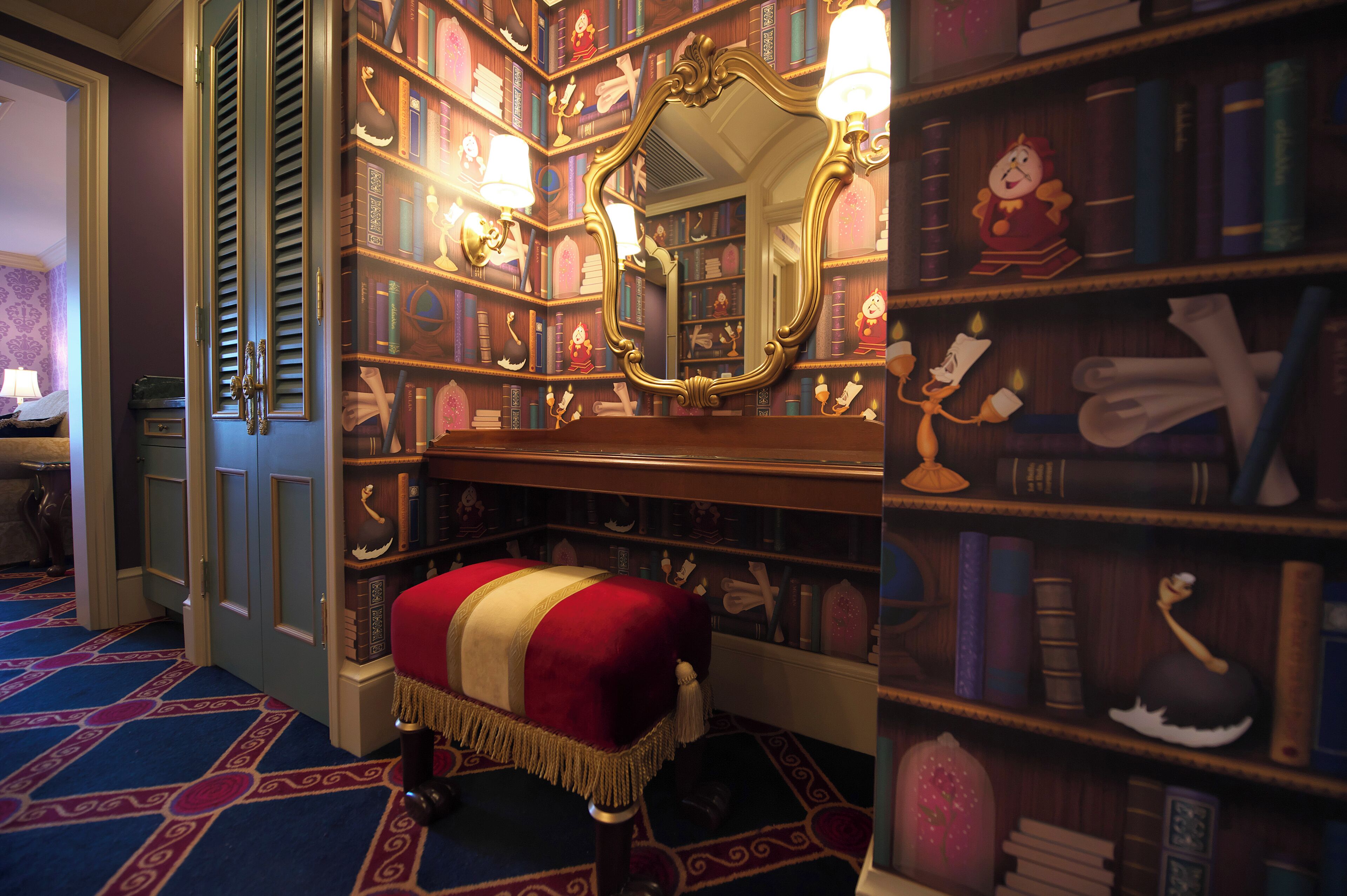 Una habitación con un espejo grande, un banco rojo y una estantería llena de libros y objetos decorativos.