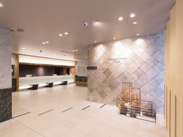 A hotel reception area with a modern design, including a reception desk, seating area, and a wall with the hotel name. - Toyama Chitetsu Hotel (Toyama)