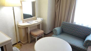 Une chambre d’hôtel avec une table ronde, un canapé, un bureau avec une lampe et un miroir.