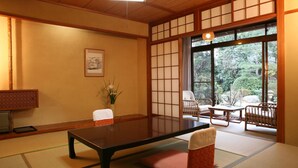 A traditional Japanese room with tatami flooring, a low table, a cushioned bench, and a sliding door leading to an outdoor area with chairs and a table. - Izumokamigami Enmusubi No Yado Konya (Matsue)