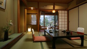 A traditional Japanese room with tatami flooring, a low table, and a sliding door. - Izumokamigami Enmusubi No Yado Konya (Matsue)