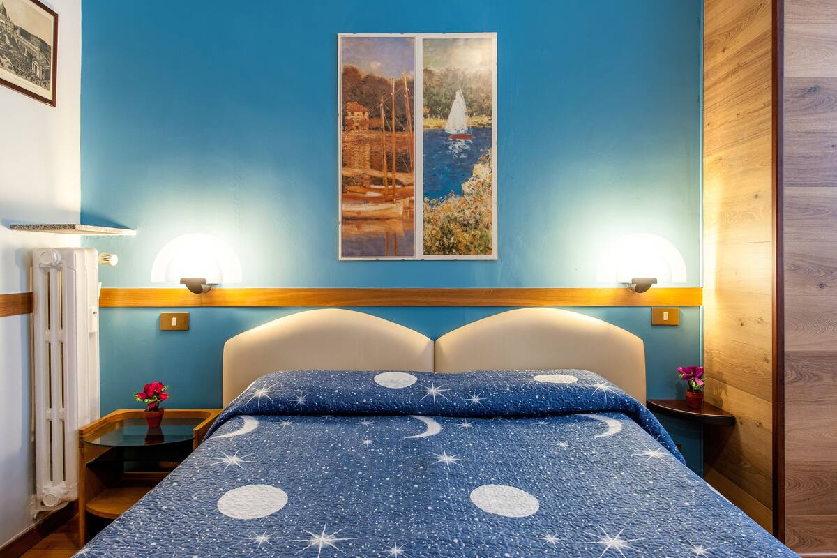 Ein Schlafzimmer mit einem Bett, zwei Nachttischen, einem Wandbild und einem Holz-Kopfteil.