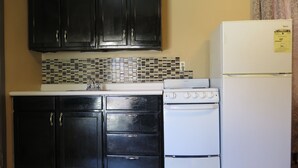 A kitchen with black cabinets, a white stove, and a white refrigerator. - Pillow Talk Motel (Wellington)