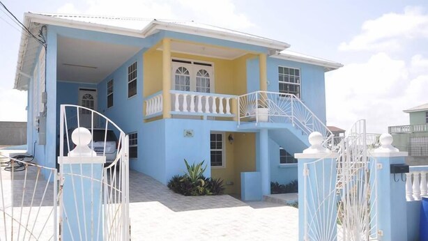 A two-story house with a balcony, a gated entrance, and a small garden area. - Princess Apartment (Mangrove)