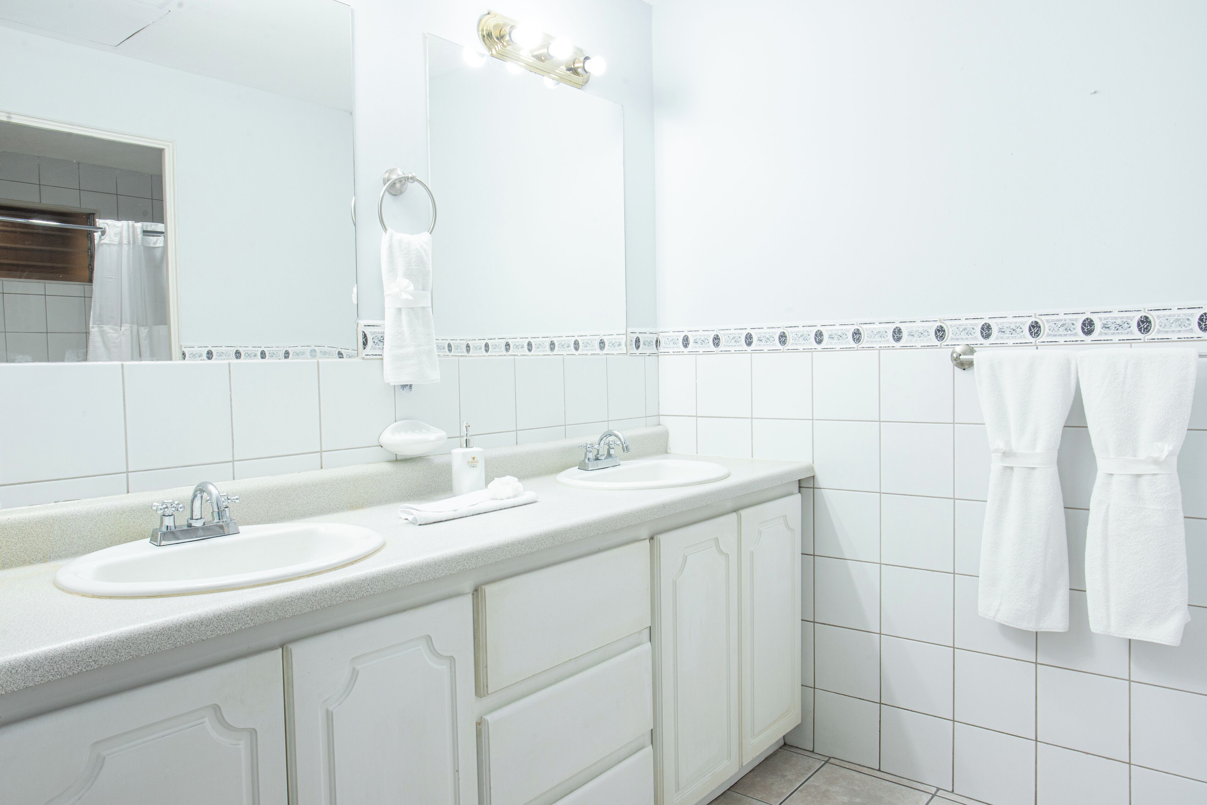 A bathroom with two sinks, a mirror, and a towel rack.