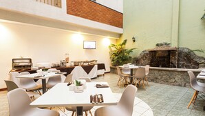 A dining area with tables and chairs, a television, and a stone fireplace.