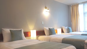 A hotel room with two beds, each with a headboard, bedside lamps, and a window with curtains.
