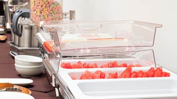A buffet setup with clear plastic containers holding various food items, including watermelon and cereal.