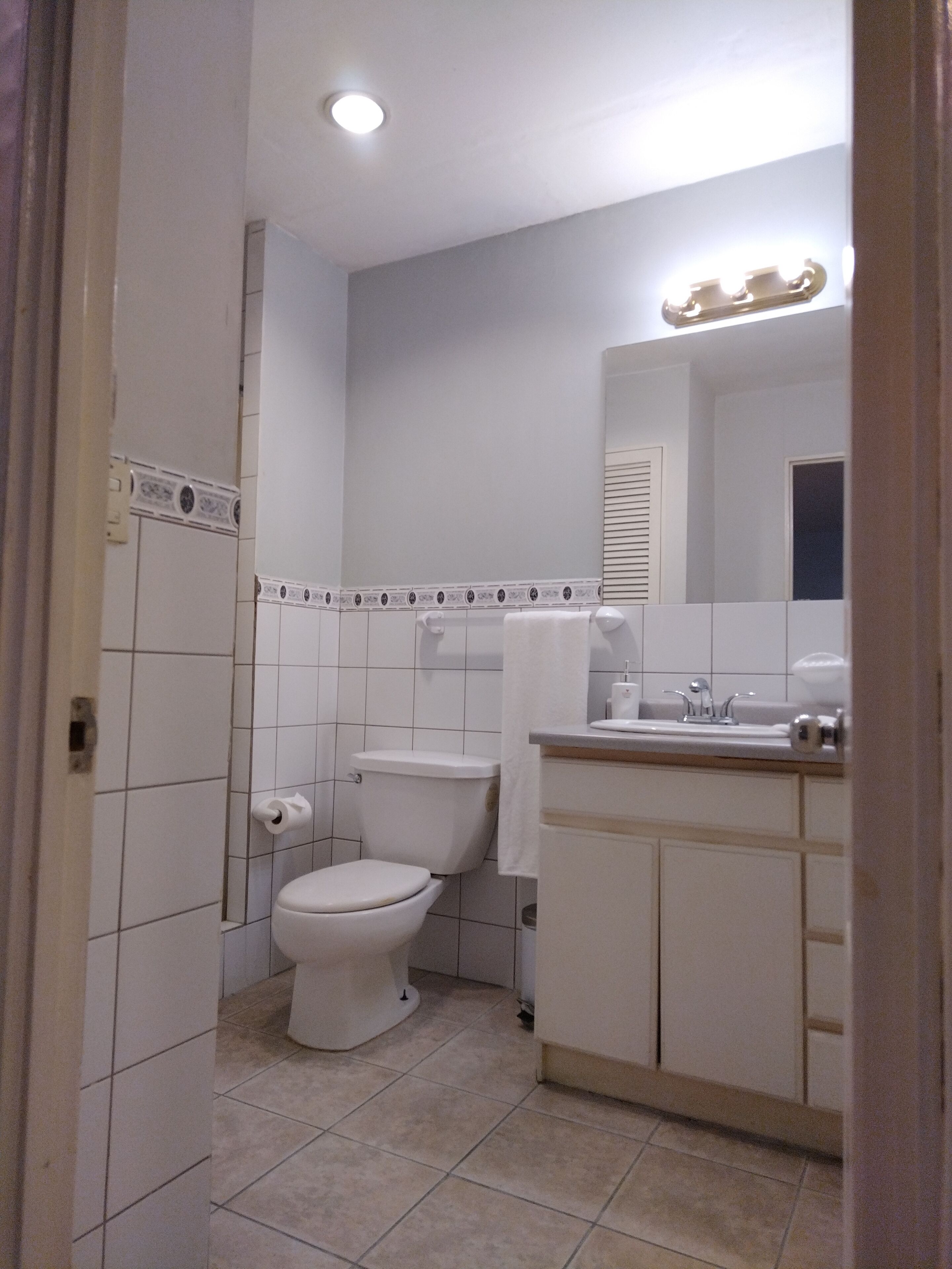A small, clean bathroom with a toilet, sink, and mirror.