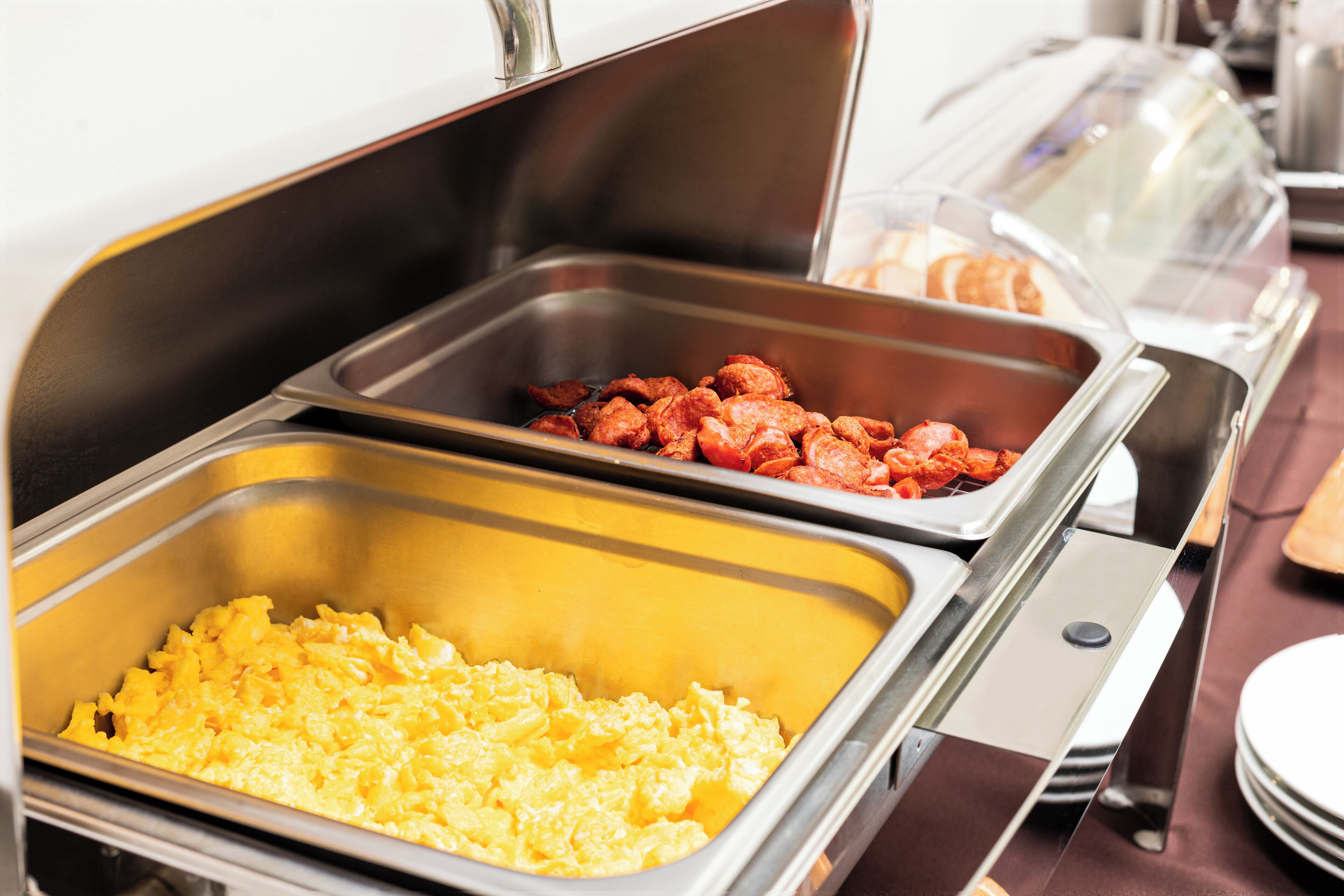 Un bufé con huevos revueltos y tocino.