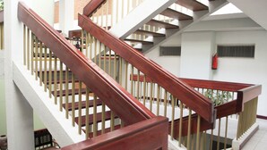 A wooden staircase with a white wall and a fire extinguisher mounted on the wall.