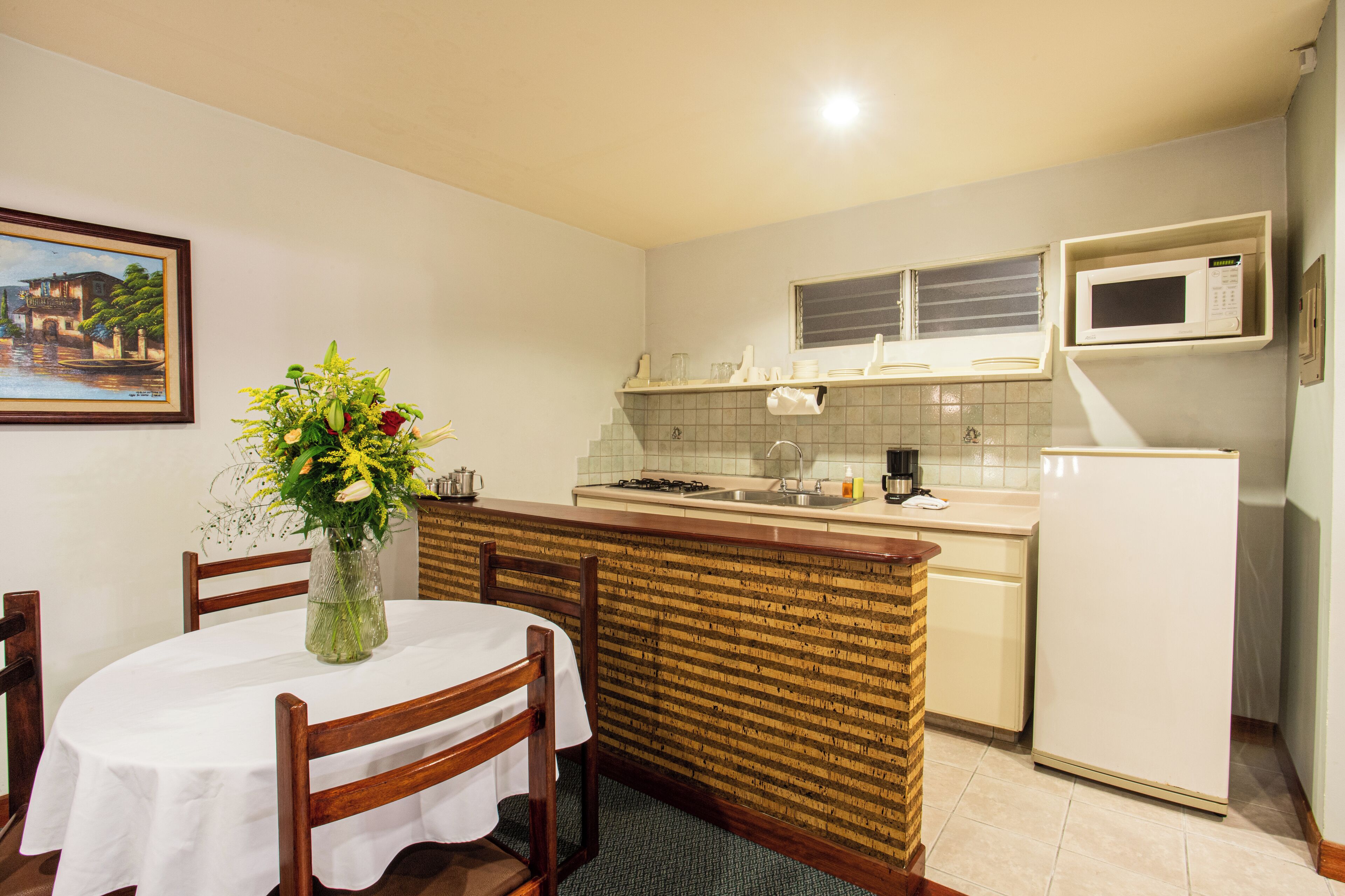 A compact kitchen with a dining area, a microwave, and a small refrigerator.