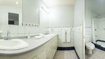 Un baño moderno con dos lavamanos, un espejo grande, una ducha y un inodoro.