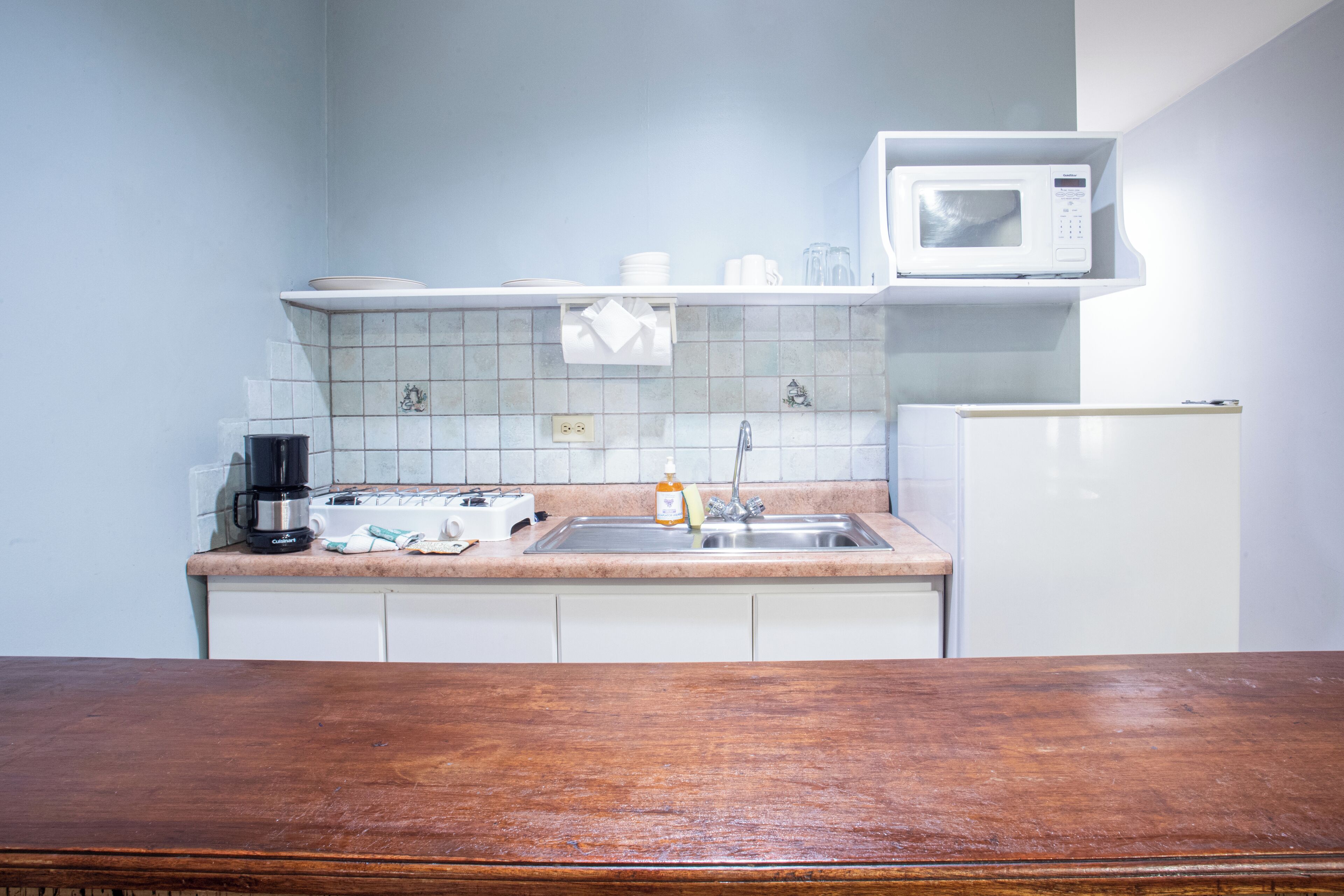 A kitchen with a microwave, coffee maker, and sink.