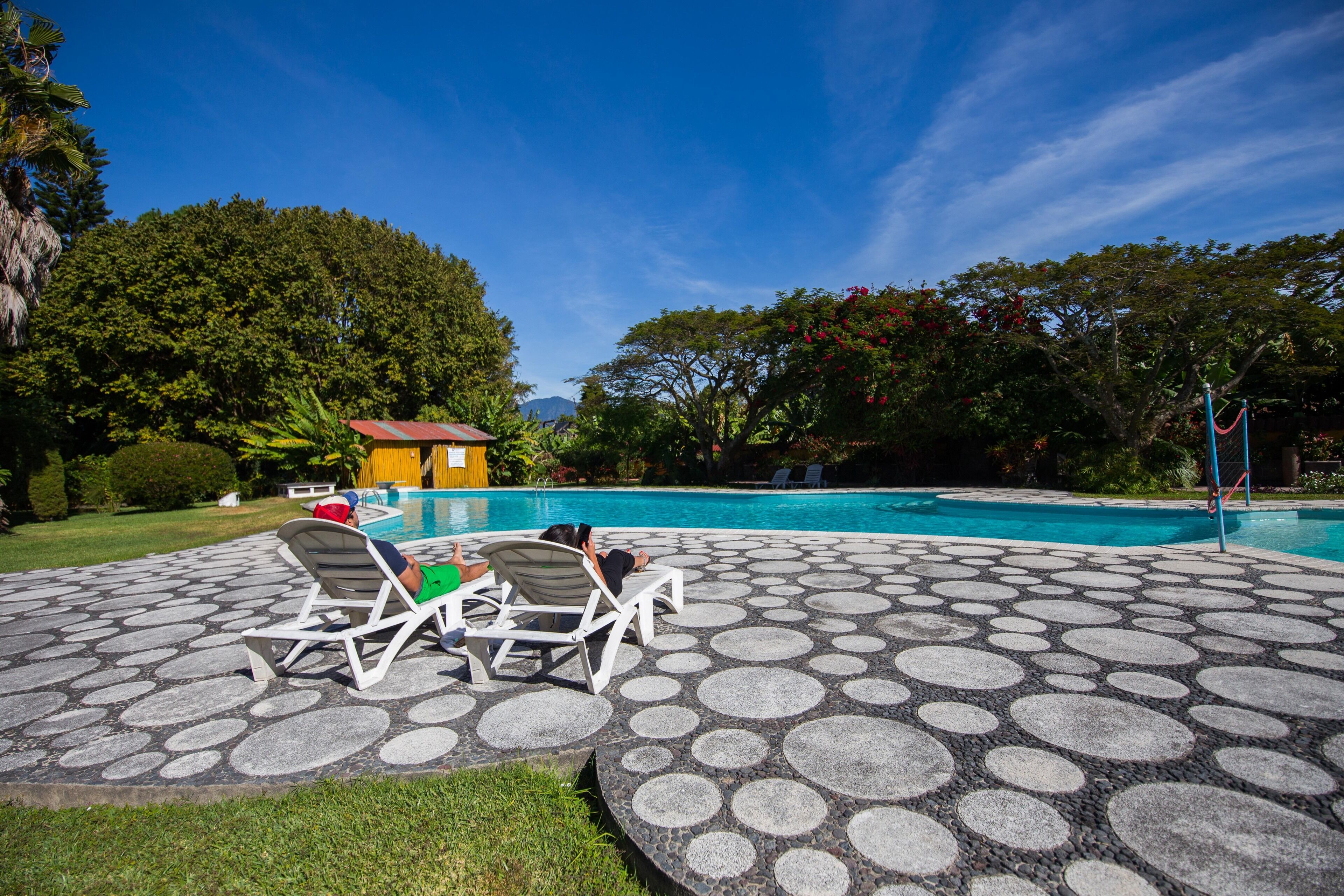 Un área de piscina con sillones de descanso y suelo de piedra con diseño.