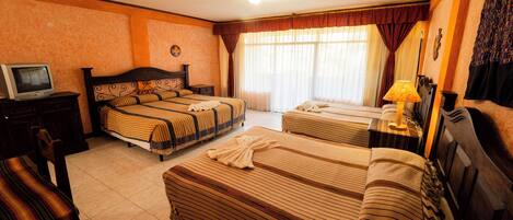 A hotel room with two beds, a TV, a lamp, and a chair.