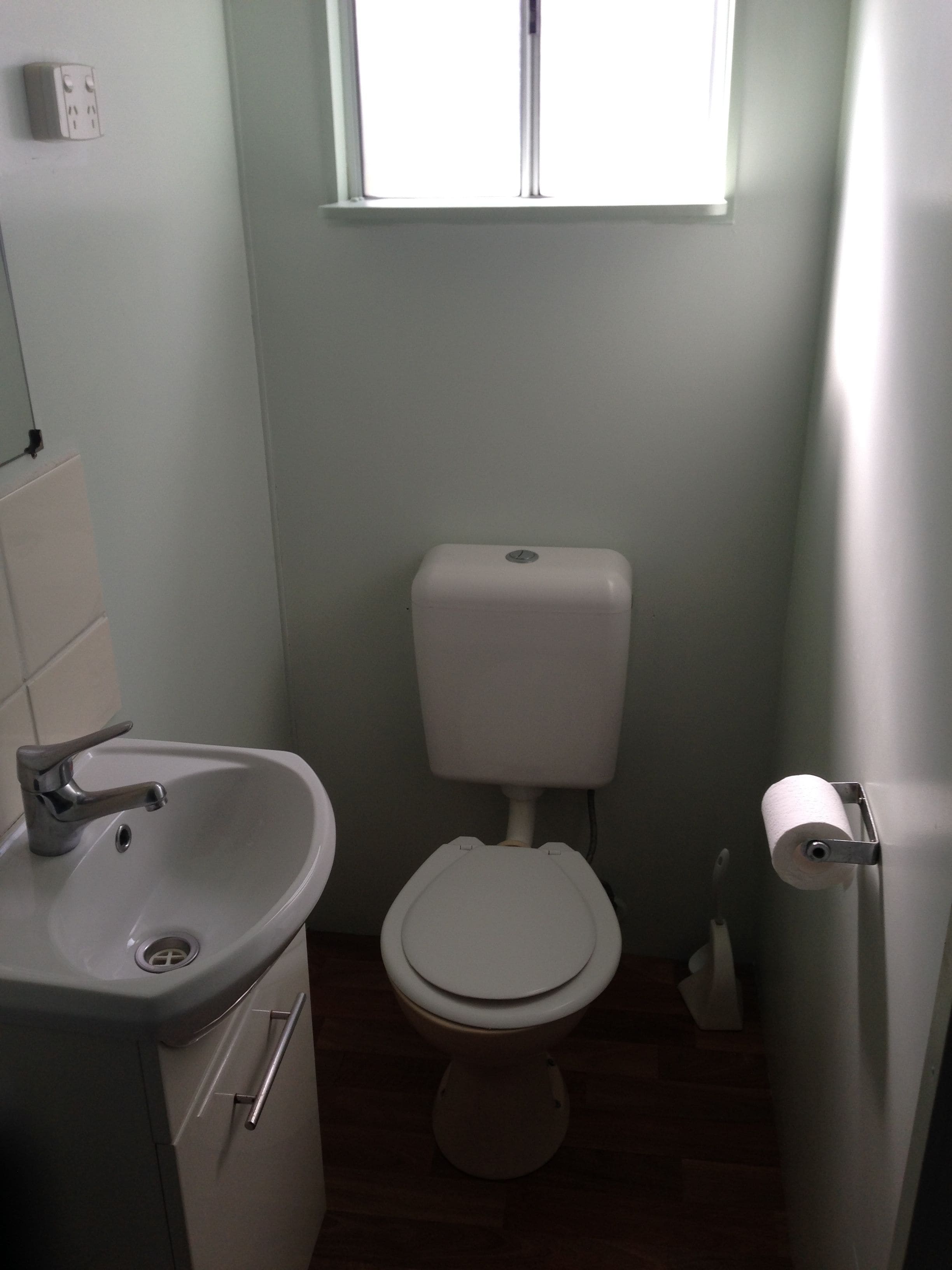 Un baño pequeño y limpio con inodoro, lavamanos y ventana.