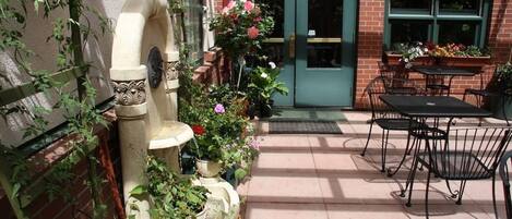 An outdoor patio with a stone fountain, potted plants, and outdoor seating.